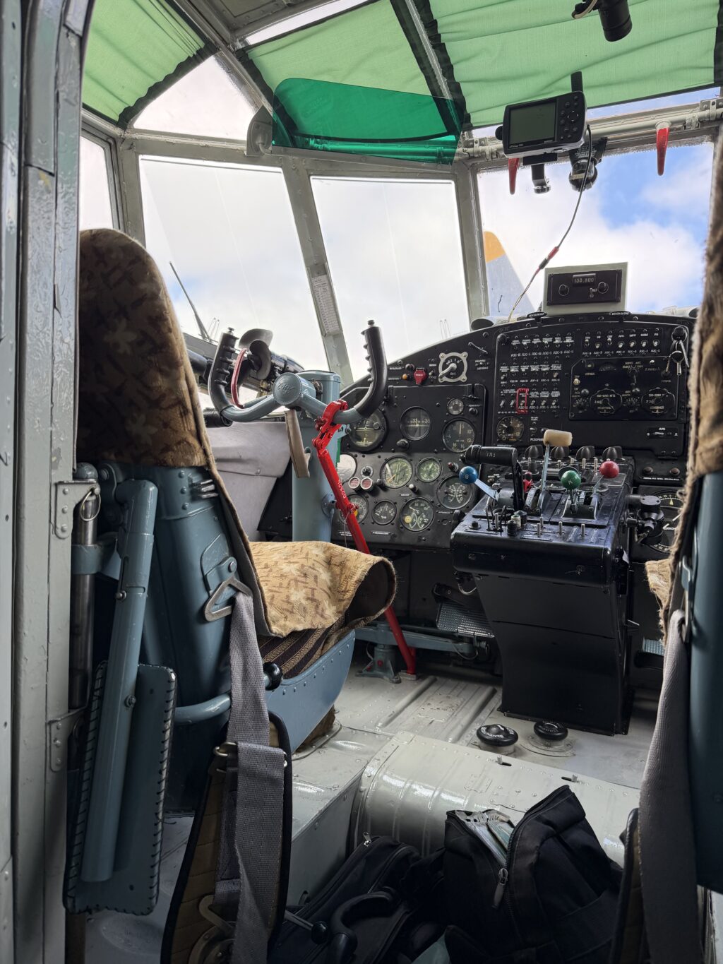 Кабина пилотов Ан-2ТП RA-02324 с двумя штурвалами, стрелочными приборами, навигатором на панели и зелёными шторками на остеклении