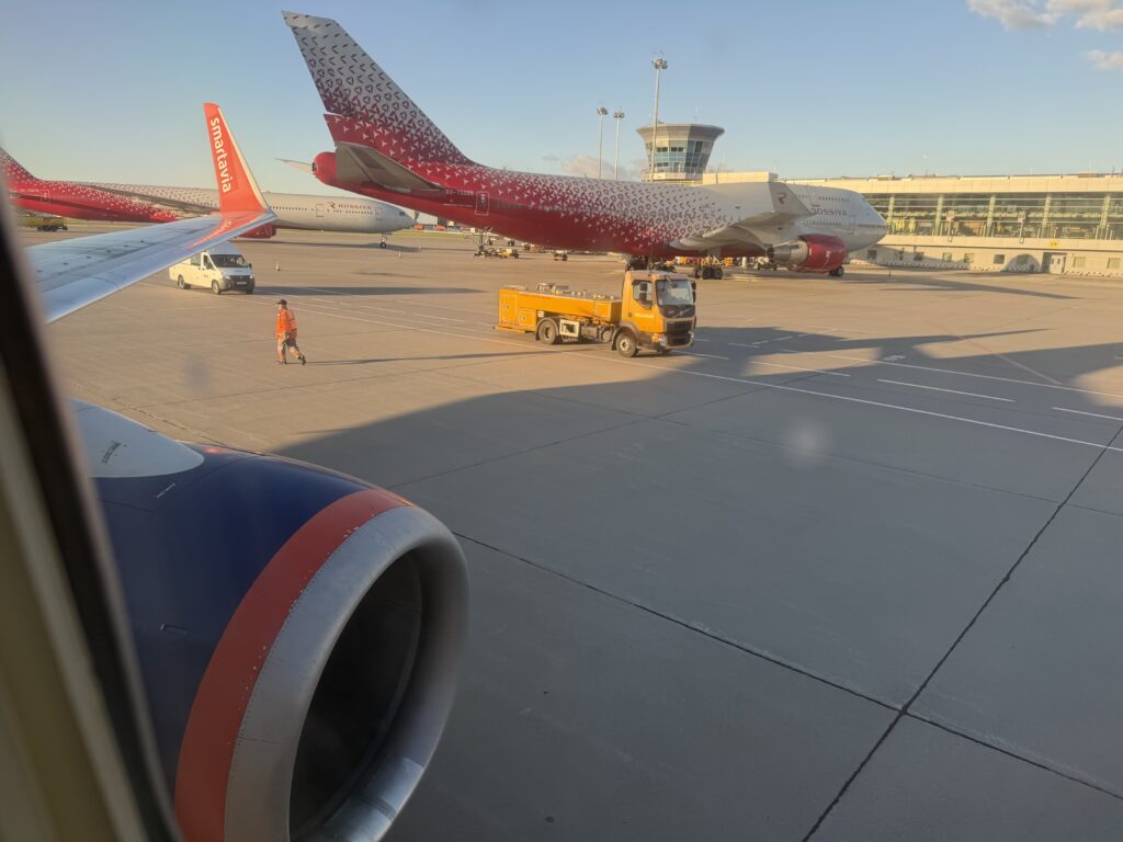 Вид из иллюминатора Boeing 737-700 Smartavia на двигатель и Boeing 747 RA-73289 «России» у терминала D Шереметьево