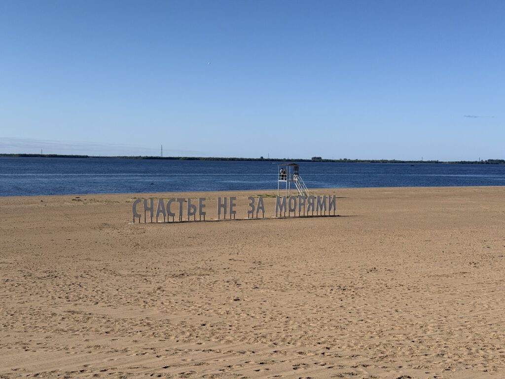 Арт-объект «Счастье не за морями» на пустом городском пляже Архангельска у Северной Двины, рядом вышка спасателей