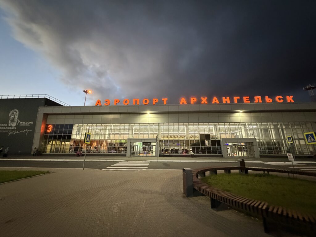 Здание аэропорта Архангельск (Талаги) вечером с подсвеченной надписью «Аэропорт Архангельск»